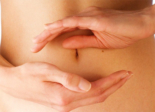 Девушка сложила ладони одна над другой на уровне живота